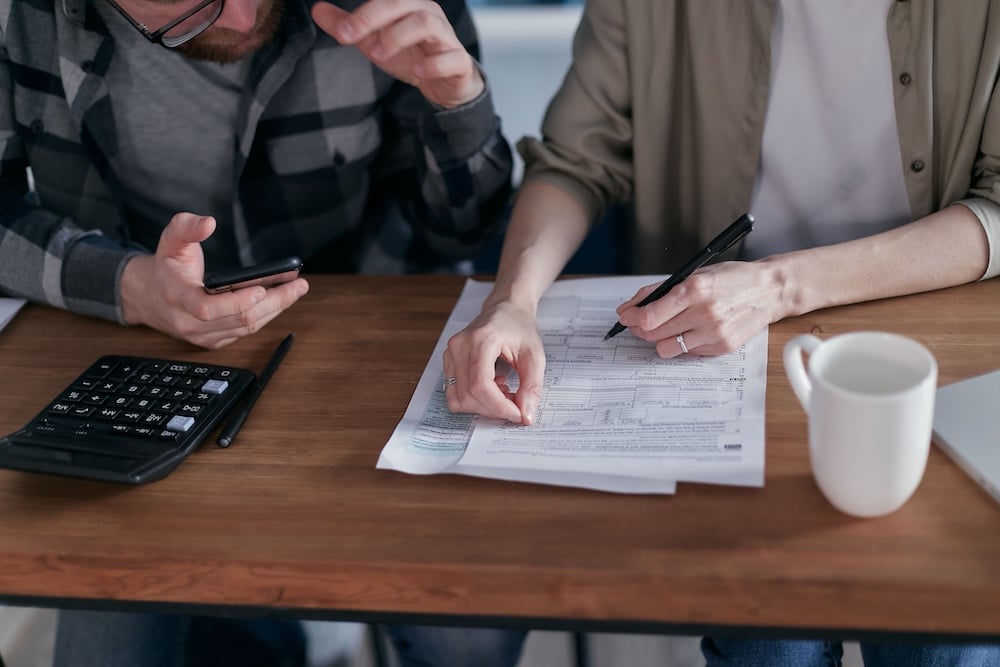 A nonprofit finance director reviewing invoices, county tax records, and a sales tax refund worksheet in a North Carolina office.